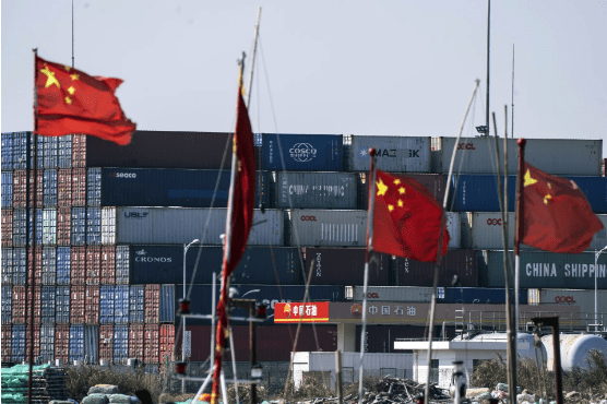 Photo of shipping containers with chinese flags in front of them